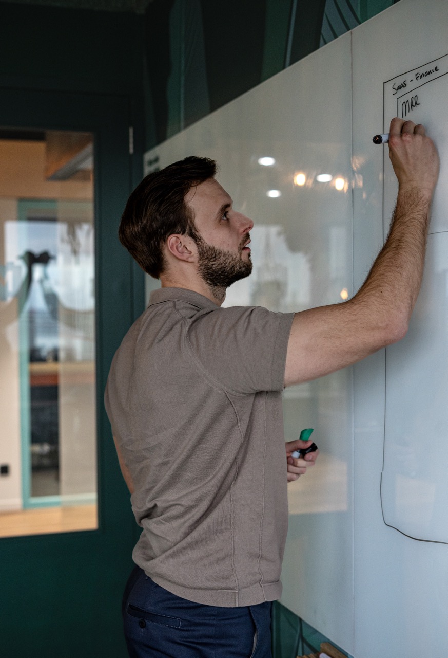 Thomas werkt een analyse uit op een whiteboard